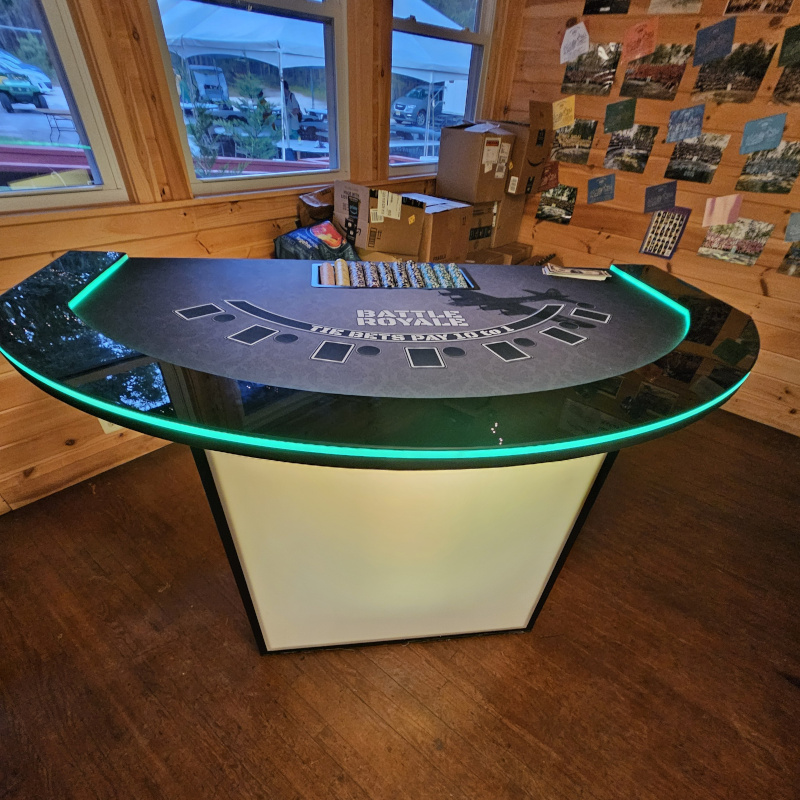 Battle Royale is our newest gaming table addition. It is played much like Casino War, but with a more exciting group-style twist: players place their bets, receive a card, and compare it against the dealer or house card to see who has the higher value. Just like Casino War, aces are high and suits do not matter, so the goal is simple — beat the dealer’s card. If your card is higher, you win; if the dealer’s card is higher, you lose; and if there is a tie, the game can move into a “battle” round where players may place an additional wager for another showdown. It is fast, easy to understand, and built around the same simple thrill of Casino War: one card, one winner, and the chance to battle again when the cards match.